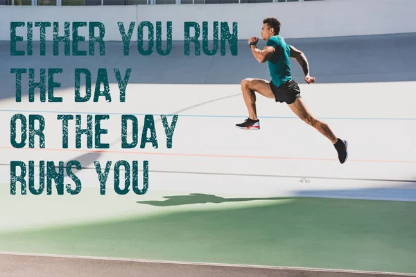 Side view of mixed race sportsman running at stadium with either you run the day or the day runs you lettering — Stock Photo