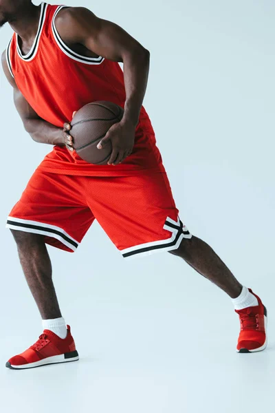 Cropped view of african american sportsman playing basketball on grey background — Stock Photo