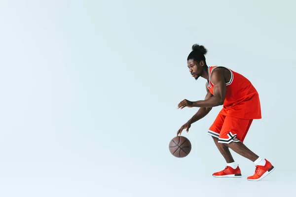Apuesto afroamericano deportista jugando baloncesto sobre fondo gris con espacio de copia - foto de stock