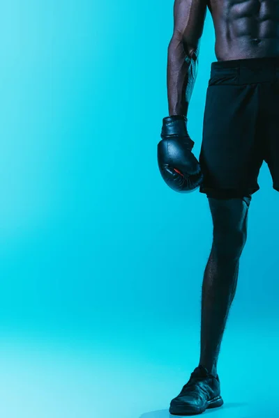 Teilansicht eines afrikanisch-amerikanischen Boxers in kurzen Hosen und Senatoren auf blauem Hintergrund — Stockfoto