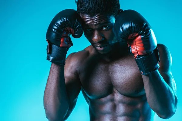 Sérieux, muscilar afro-américain boxer posant à la caméra sur fond bleu — Photo de stock