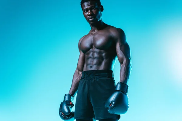 Sem camisa, muscular afro-americano boxer posando para câmera no fundo azul — Fotografia de Stock