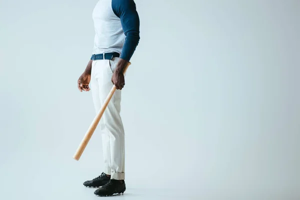 Vista parcial del deportista afroamericano con bate de béisbol sobre fondo gris - foto de stock