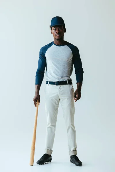 Handsome african american baseball player posing at camera on grey background — Stock Photo