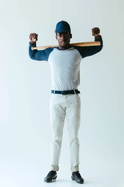 Confiado jugador de béisbol afroamericano mirando a la cámara sobre fondo gris - foto de stock