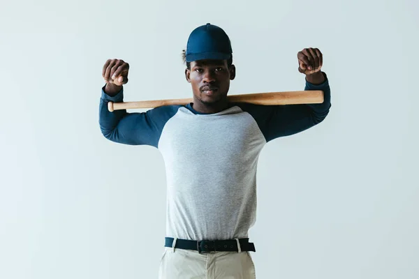 Confiante atleta afro-americano com bastão de beisebol olhando para a câmera isolada em cinza — Fotografia de Stock