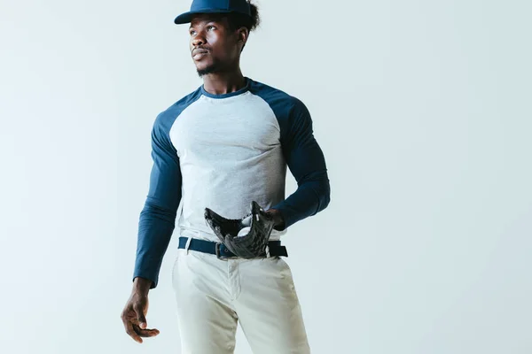 Серйозний Африканський американський спортсмен з бейсбольною рукавичкою і м'ячем дивлячись ізольовані на сірий — стокове фото