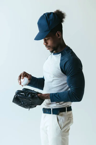 Handsome african american sportsman in baseball glove holding ball isolated on grey — Stock Photo