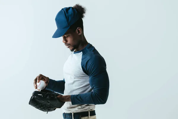 Handsome african american sportsman in baseball glove holding ball isolated on grey — Stock Photo