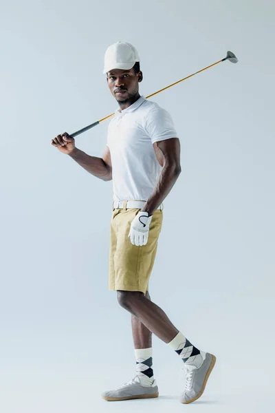 Confiado jugador de golf afroamericano mirando a la cámara sobre fondo gris - foto de stock