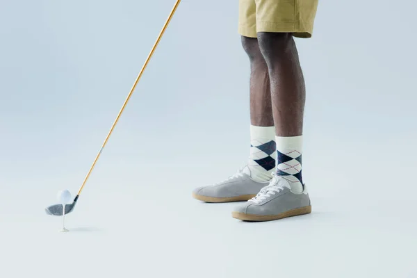 Обрізаний вид афроамериканського спортсмена, який грає в гольф на сірому фоні — стокове фото