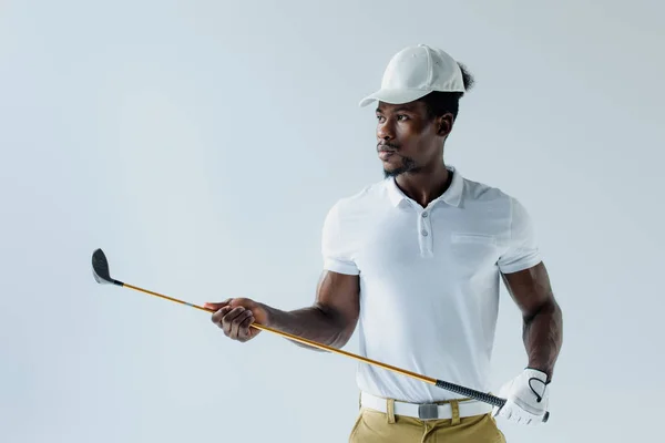 Sportif afro-américain sérieux tenant club de golf isolé sur gris — Photo de stock