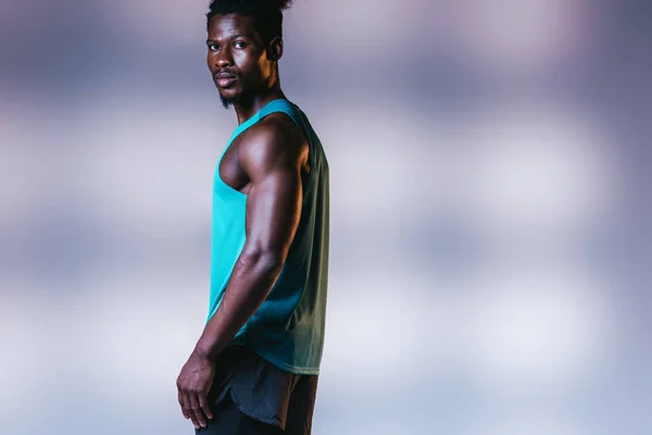 Bonito, confiante Africano americano desportista olhando para a câmera no fundo cinza com iluminação — Fotografia de Stock