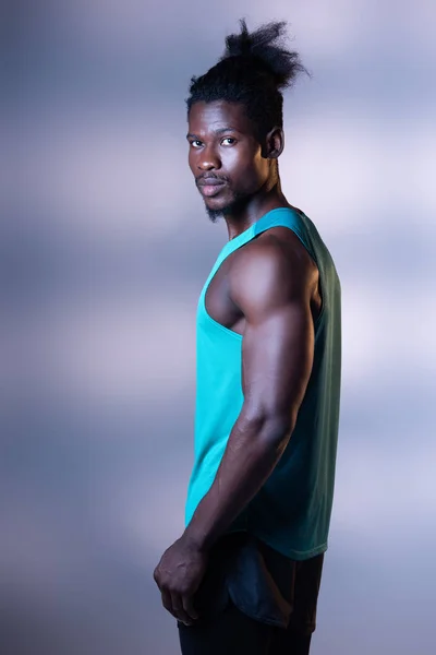 Bonito, muscular afro-americano desportista posando para câmera no fundo cinza com iluminação — Fotografia de Stock