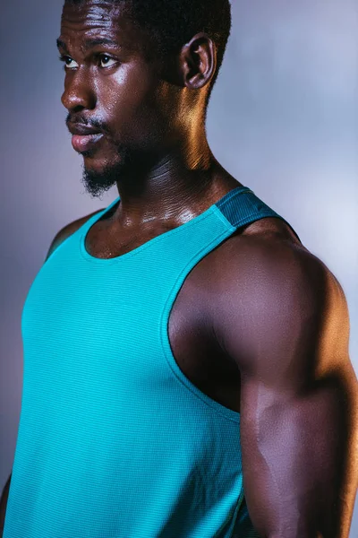 Fiducioso, atletico sportivo afroamericano guardando altrove su sfondo grigio e blu sfumato con illuminazione — Foto stock