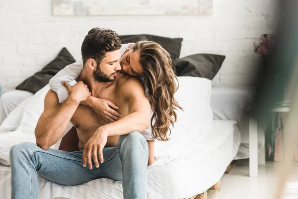 Enfoque selectivo de dos personas enamoradas abrazándose mientras están sentadas en la cama - foto de stock