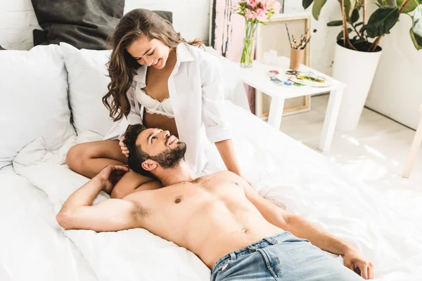 Junges Paar sitzt im Bett und schaut einander an — Stockfoto