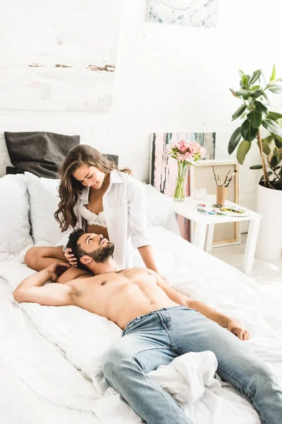 Sexy pareja sentado en acogedora cama y mirándose el uno al otro - foto de stock