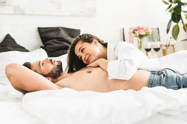 Junges Paar liegt im Bett, während Mädchen lächelt und Mann ansieht — Stockfoto