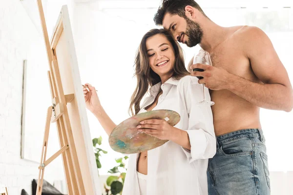 Bajo ángulo vista de chica dibujo con pincel mientras el hombre de pie detrás de la novia - foto de stock