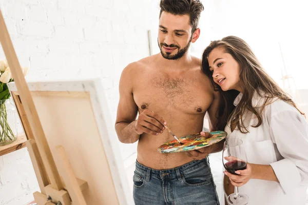 Selective focus of sexy young couple of artists looking at painting — Stock Photo