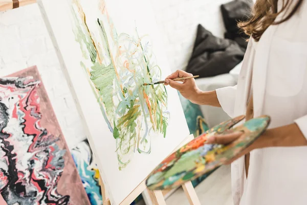 Cropped view of young girl drawing with brush and holding palette — Stock Photo