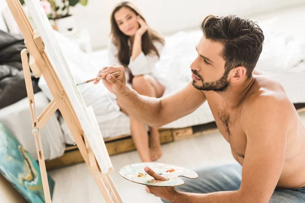 Enfoque selectivo de sexy hombre sin camisa dibujo y chica sentada en la cama - foto de stock