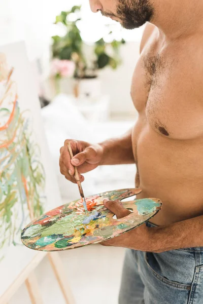 Cropped view of sexy muscular man drawing with brush and colorful paints — Stock Photo