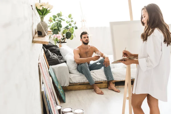 Selektiver Fokus des Mannes, der mit Wein und schönem Mädchen im Bett sitzt — Stockfoto