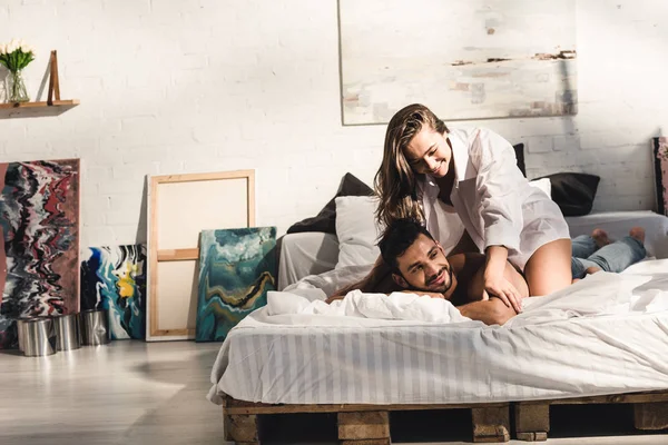 Feliz joven pareja riendo mientras chica sentado en espalda de sin camisa hombre - foto de stock