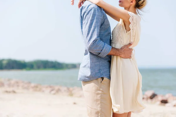 Vista recortada de pareja romántica abrazándose en la playa - foto de stock