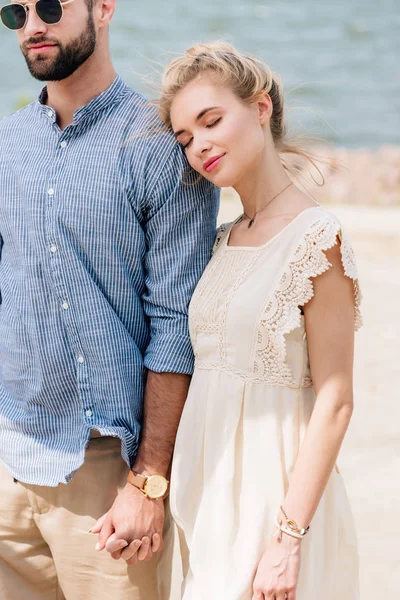 Blonde girl with closed eyes leaning on boyfriend shoulder at beach — Stock Photo