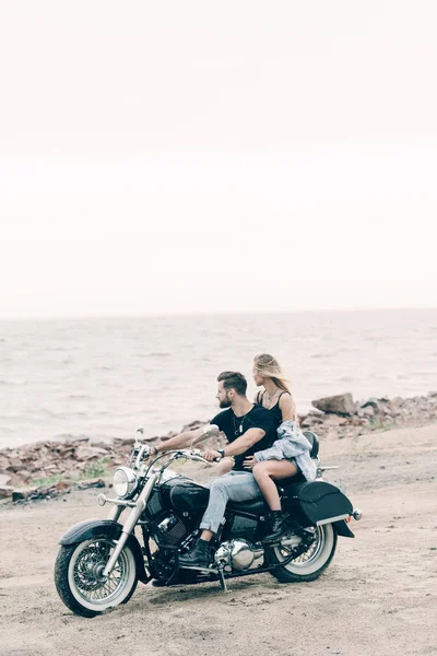 Young couple of bikers on black motorcycle near river — Stock Photo