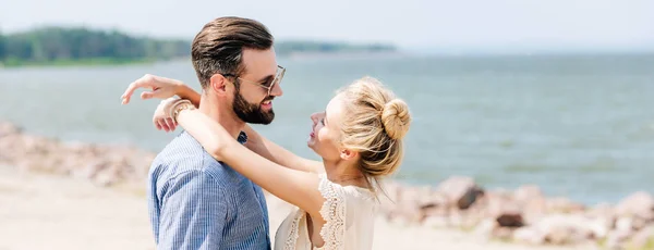 Schönes Paar, das sich am Strand umarmt und ansieht, Panoramaaufnahme — Stockfoto