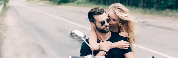 Joven pareja de ciclistas abrazando de cerca en negro motocicleta, tiro panorámico - foto de stock