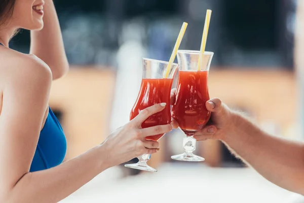 Vista cortada de sorrir jovem mulher clinking copos de bebida refrescante com namorado — Fotografia de Stock