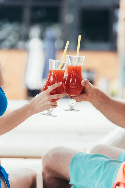 Vista parcial de novia y novio tintineo vasos de bebida refrescante - foto de stock