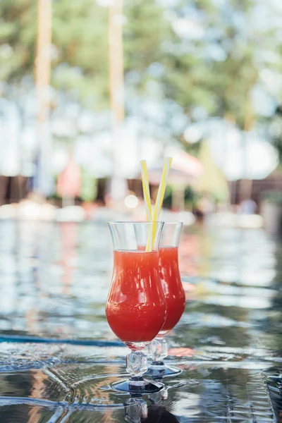 Дві склянки зі смачними, натуральними фруктовими напоями на березі басейну — стокове фото