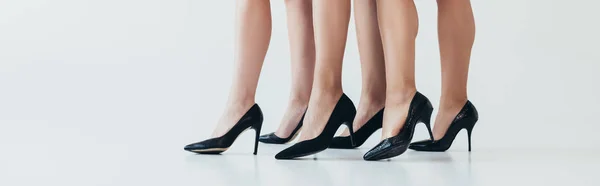 Plano panorámico de tres mujeres con zapatos negros de tacón alto en gris - foto de stock