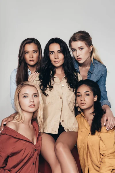 Front view of five attractive multiethnic feminists in colorful shirts looking at camera isolated on grey — Stock Photo