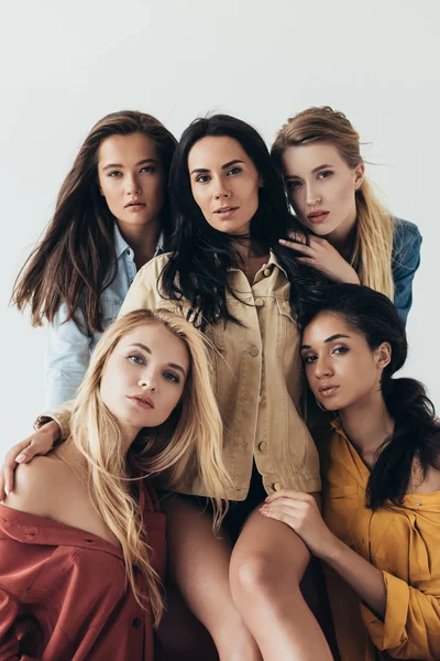 Front view of five attractive multiethnic feminists in colorful shirts embracing and looking at camera isolated on grey — Stock Photo