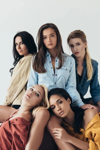 Front view of five attractive multiethnic feminists in colorful shirts embracing and looking at camera isolated on grey — Stock Photo