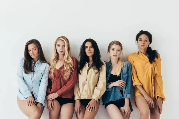 Front view of five sexy multiethnic feminists in colorful shirts looking at camera isolated on grey — Stock Photo