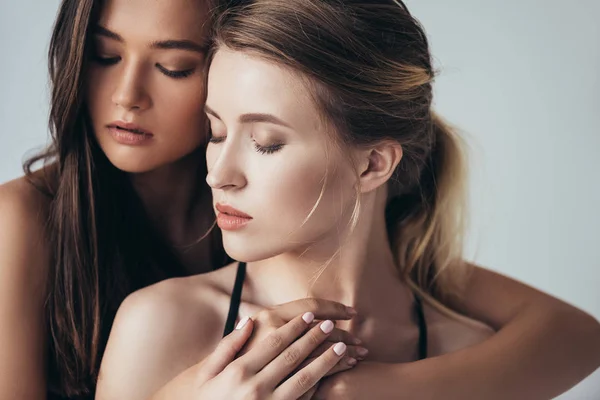 Two attractive feminists embracing with closed eyes isolated on grey — Stock Photo