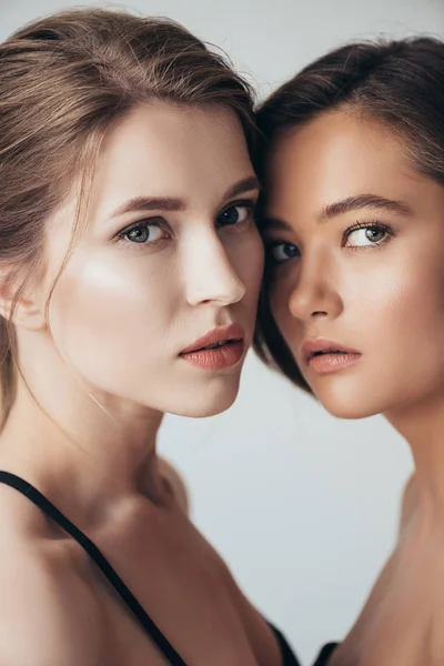Zwei attraktive junge Frauen, die isoliert auf grau in die Kamera blicken — Stockfoto