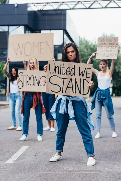 Piena vista lunghezza di femminista tenuta cartello con iscrizione unita ci troviamo vicino alle donne in strada — Foto stock