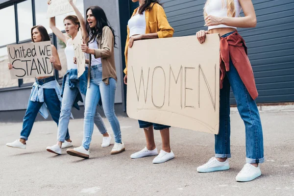 Vista recortada de feministas sosteniendo pancarta con la palabra mujeres en la calle - foto de stock