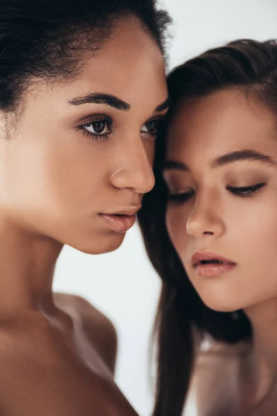 Dos atractivas mujeres jóvenes multiétnicas mirando hacia otro lado aisladas en gris — Stock Photo