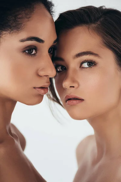 Zwei attraktive multiethnische junge Frauen, die isoliert auf grau schauen — Stockfoto