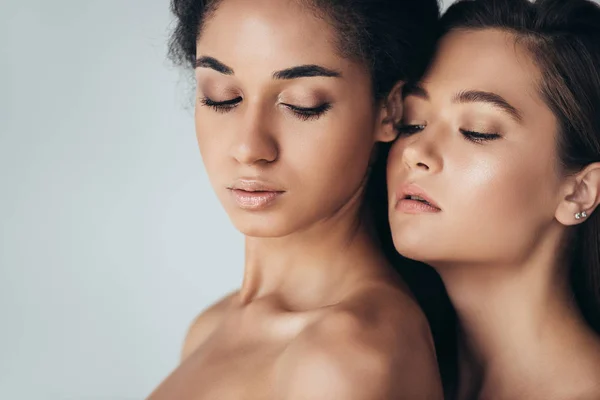 Zwei attraktive multiethnische junge Frauen mit geschlossenen Augen isoliert auf grau — Stockfoto